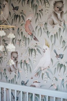 a baby's crib with wallpaper featuring koalas and other animals