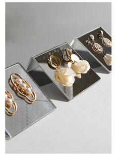 three metal trays with different types of jewelry on them