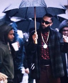 a man holding an umbrella while standing in front of other people on the side walk