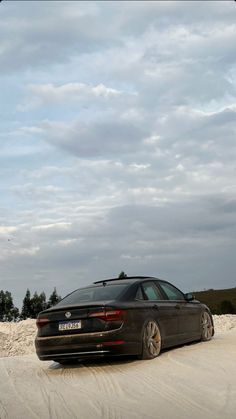 a car parked in the sand on a cloudy day with no one around looking at it