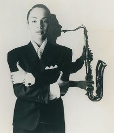 a man in a suit and tie holding a saxophone