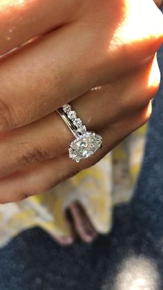 a woman's hand with a diamond ring on her finger and an engagement band