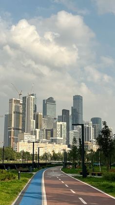 an empty road in front of a large city with tall buildings on the other side