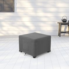 a gray ottoman sitting on top of a white floor next to a table and chair