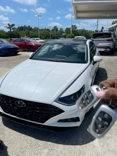 a white car is being held up by someone's hand in a parking lot