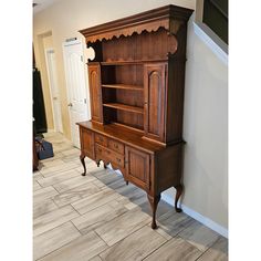 an old wooden cabinet sitting in the corner of a room with tile flooring and white walls