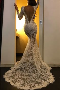 a woman in a white wedding dress standing in front of a doorway with her arms outstretched