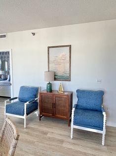 a living room with two blue chairs and a wooden cabinet in it's center