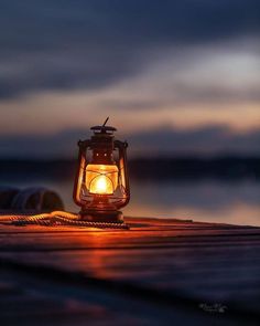 a lit lantern sitting on top of a wooden dock