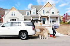 a woman unloading items from the back of a white truck in front of a house