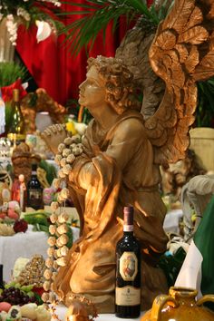 an angel statue next to a bottle of wine on a table filled with other items