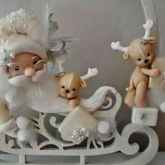 three small figurines are sitting on a sleigh with santa claus and other decorations