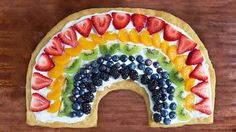 a rainbow fruit pizza is shown with the words rainbow written in white and surrounded by pictures of different fruits