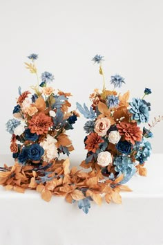 two vases filled with flowers sitting on top of a white cloth covered tablecloth