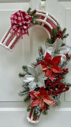 a wreath with poinsettis and bows hanging on a door