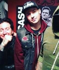 three young men standing next to each other in front of a red wall with posters on it