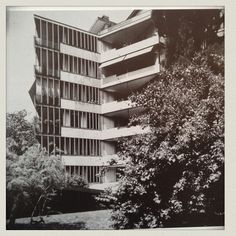 an old black and white photo of a building with trees in front of the building