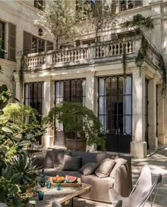 an outdoor living room with lots of furniture and potted plants in front of the house