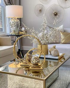 a living room filled with furniture and a glass coffee table covered in gold decor items