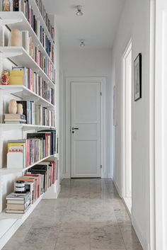 a long white bookcase filled with lots of books next to a doorway and door