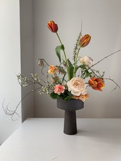 a vase filled with lots of flowers on top of a white table next to a wall