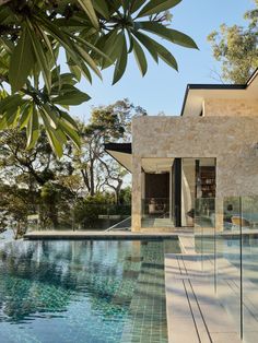 an outdoor swimming pool next to a house with glass walls and doors on both sides