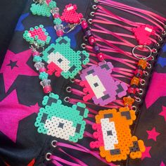 several pieces of bead art are laying on top of a black bag with pink, blue, and green beads