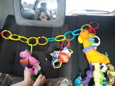 a child's hand is holding onto toys in the back seat of a car