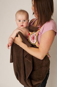 a woman holding a baby wrapped in a brown towel