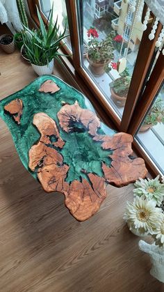 a table that has some flowers in it on a wooden floor next to a window