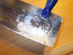 a person using a shovel to dig in dirt on a wooden table with a blue handle