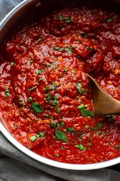 a wooden spoon in a pot filled with marinara sauce