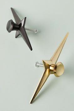 two gold and black metal objects on a white surface with screws in the shape of an airplane