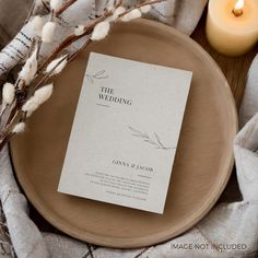 a wedding program sitting on top of a wooden plate next to a candle and some cotton