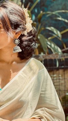 a woman in a white sari holding a cell phone and looking off into the distance