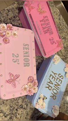 three pink and blue notebooks sitting on top of a marble counter next to each other