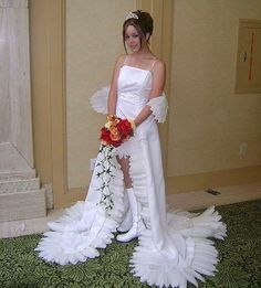 a woman in a white wedding dress standing next to a flower bouquet on the floor