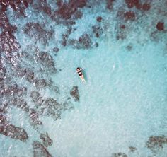 an aerial view of a person swimming in the ocean with rocks and water around them