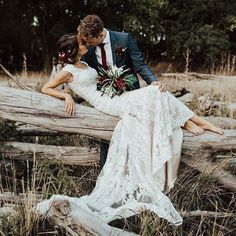 a bride and groom are sitting on a log