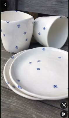 three white dishes with blue flower designs on them sitting on a wooden table next to each other