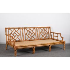 a bamboo bench with an upholstered back and seat cushion on the bottom, in front of a white wall