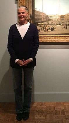 an older woman standing in front of a painting