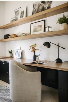 a desk with a chair, lamp and pictures on the wall above it in a home office