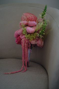 a bouquet of pink flowers sitting on top of a white couch next to a green plant