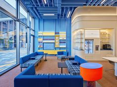 an office lobby with blue couches and orange stools in front of large windows