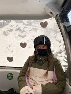 a woman sitting in front of a window with hearts drawn on the wall behind her