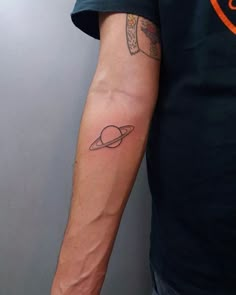 a man with a small saturn tattoo on his arm