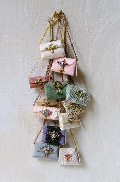 a bunch of small purses hanging on a white wall with chains attached to them