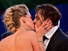 a man and woman kissing each other on the red carpet in front of an audience