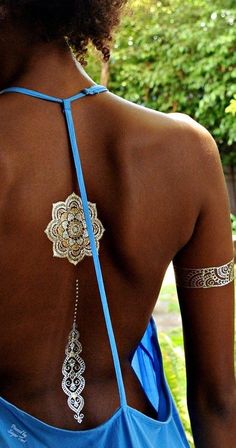 the back of a woman wearing a blue dress with an intricate design on her chest